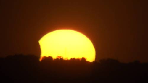 Das Bild zeigt den Sonnenuntergang mit einer Teilabdeckung der Sonne durch den Mond